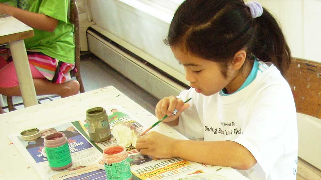 A child glazing her ceramic art