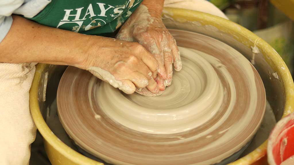 A woman wheel-throwing a ceramic bowl