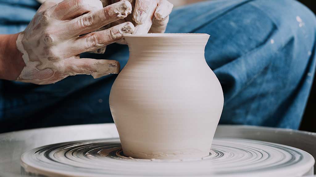 A wheel-thrown vase taking shape as the artist carefully finalizes the spout