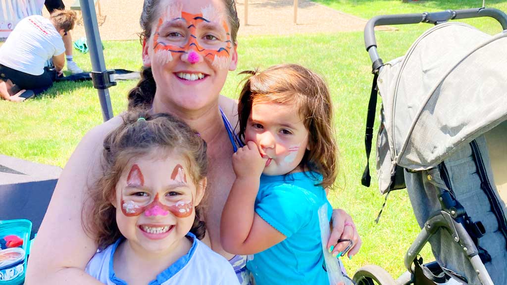 A young mother with her two daughters who all had their faces painted as various cats