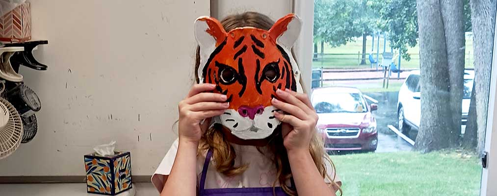 A girl wearing the tiger mask she made in class