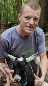 Zach Duncan-Tessmer holding a baby goat in his lap
